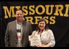 Mendez accepts the Journalist of the Year award from Missouri Press Association President Bryan Chester, left. 